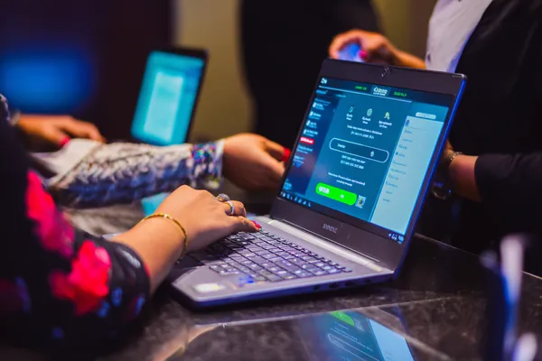 A confident dealer surrounded by casino chips inviting players to access their 1XBED account, reflecting quick and easy login options.